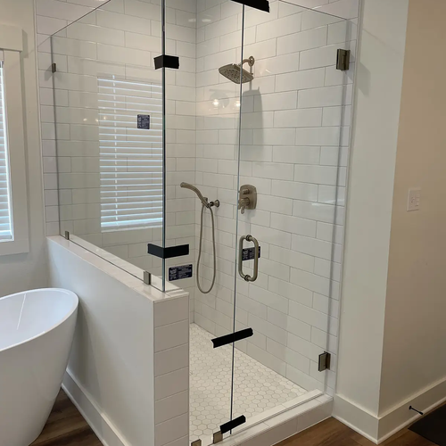 Shower enclosure with subway tiles and glass doors by Dunn's Flooring Depot