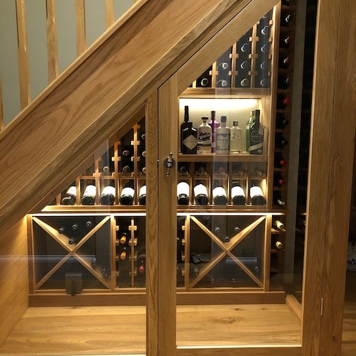 Custom glass and wood wine room under the stairs by Dunn's Flooring Depot Showroom & Design